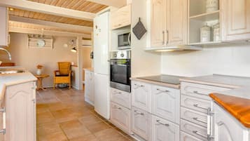 A kitchen with white cabinetry, a built-in oven, and a wooden countertop.