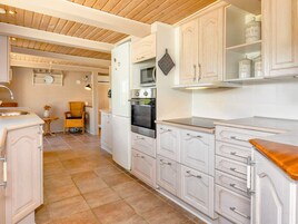 A kitchen with white cabinetry, a built-in oven, and a wooden countertop.