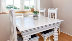 A white dining table with two chairs, a potted plant, and a window with a view of greenery. - 5 Person Holiday Home in Karby (Øster Assels)