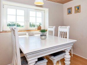 A white dining table with two chairs, a potted plant, and a window with a view of greenery. - 5 Person Holiday Home in Karby (Øster Assels)