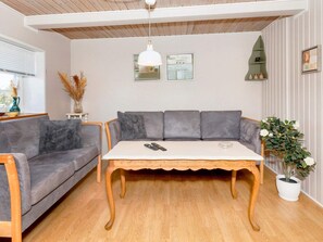 A modern living room with a grey sofa, a wooden coffee table, and a potted plant.