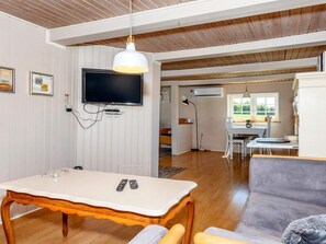 A room with a wooden ceiling, a television mounted on the wall, a dining table with chairs, and a sofa. - 5 Person Holiday Home in Karby (Øster Assels)