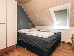 Un dormitorio con cama, armario, radiador y ventana.