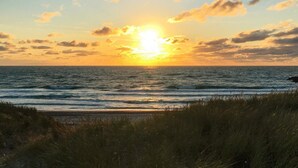 A sunset over the ocean with waves and grassy foreground. - 12 Person Holiday Home in Thyboron (Thyborøn)