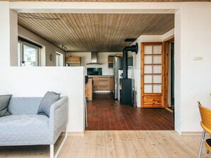A modern interior with a sofa, wooden flooring, and a kitchen area with cabinets and a stove. - 12 Person Holiday Home in Thyboron (Thyborøn)