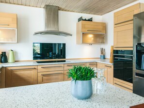 Cozinha moderna com armários de madeira, coifa de aço inoxidável e bancada de granito.