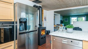 A modern kitchen with stainless steel appliances, a wood-burning stove, and a dishwasher. - 12 Person Holiday Home in Thyboron (Thyborøn)