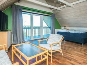 Una habitación con cama, una silla, una mesa y un balcón con vistas.