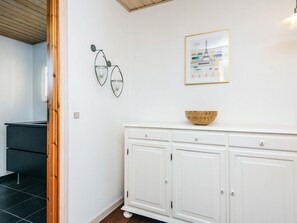 Un mueble blanco con un cuenco de madera encima, un cuadro enmarco de París y dos lámparas fijadas a la pared.