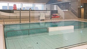 An indoor swimming pool with a tiled floor, a metal railing, and a staircase leading to a sauna area. - 12 Person Holiday Home in Thyboron (Thyborøn)