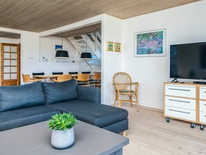 Una sala de estar moderna con un sofá, una televisión y un comedor con sillas y una mesa.