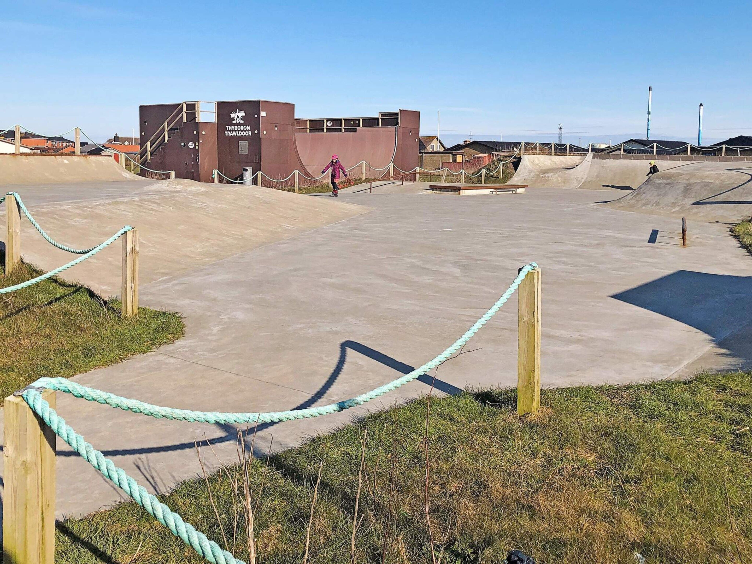An outdoor skate park with concrete ramps and a building labeled 'Thyboron Trawdoor'.