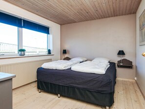 A bedroom with a bed, two bedside lamps, a window with blinds, a radiator, and a small table. - 12 Person Holiday Home in Thyboron (Thyborøn)