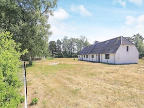 A white building with a sloped roof, surrounded by a grassy field and trees. - 6 Person Holiday Home in Laeso (Læsø)
