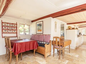 A dining area with a red tablecloth, wooden chairs, a bench, and a wall-mounted plate rack. - 6 Person Holiday Home in Laeso (Læsø)
