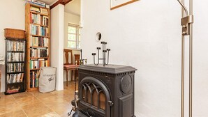 A cozy room with a wood-burning stove, a bookshelf, and a chair. - 6 Person Holiday Home in Laeso (Læsø)