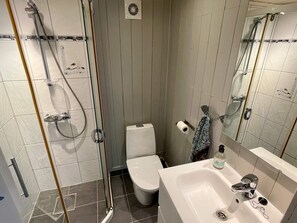 A bathroom with a shower, toilet, sink, and mirror.