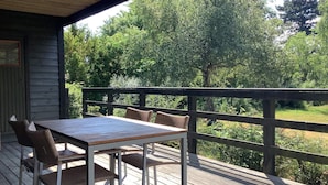 A wooden deck with a table and chairs, overlooking a lush green landscape.
