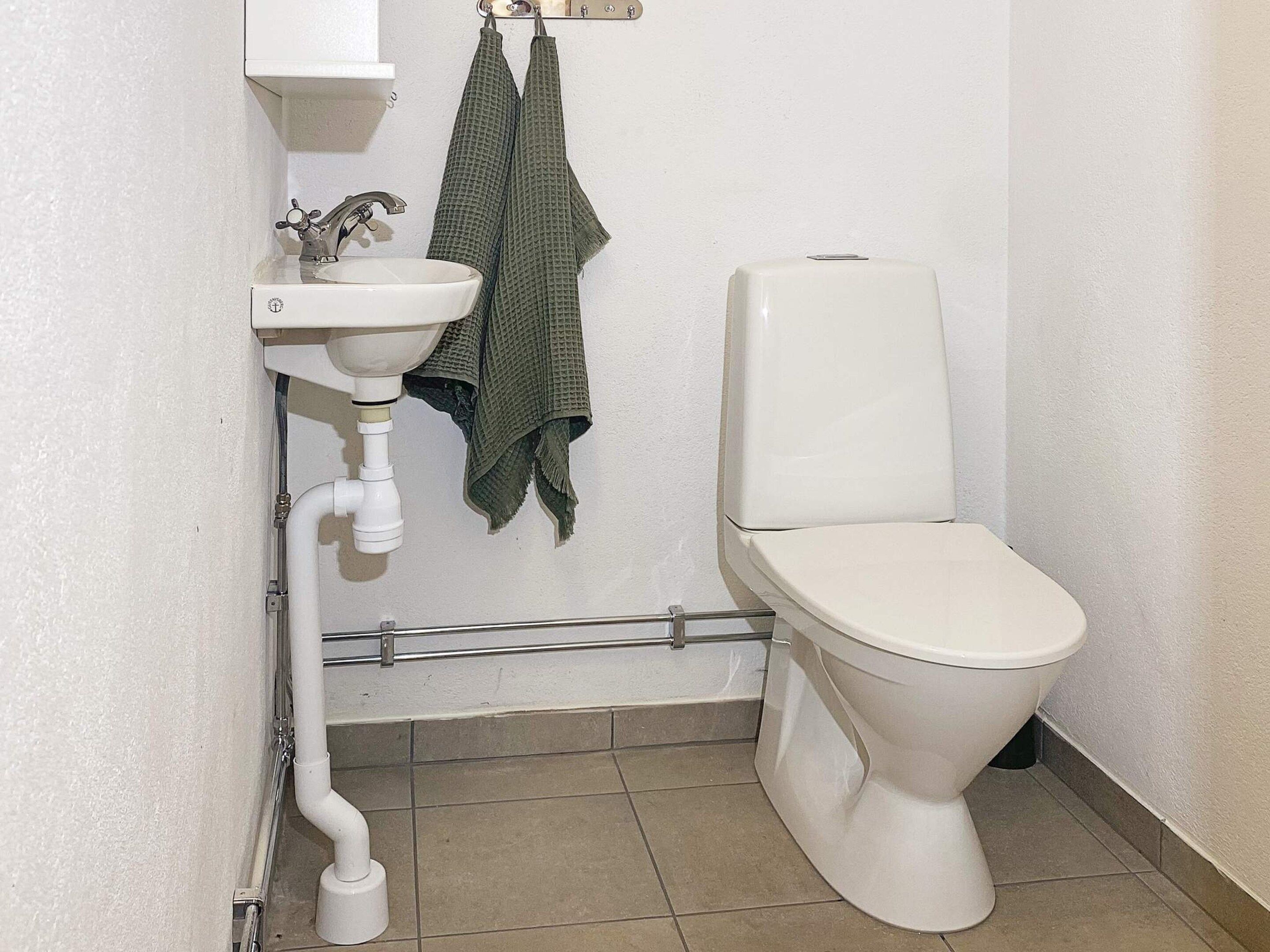 Une salle de bain avec un lavabo blanc, des toilettes et un porte-serviettes.