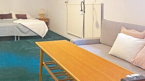 A hotel room with a bed, a sofa, a wooden table, and a lamp. - 6 Person Holiday Home in Solvesborg (Sölvesborg)