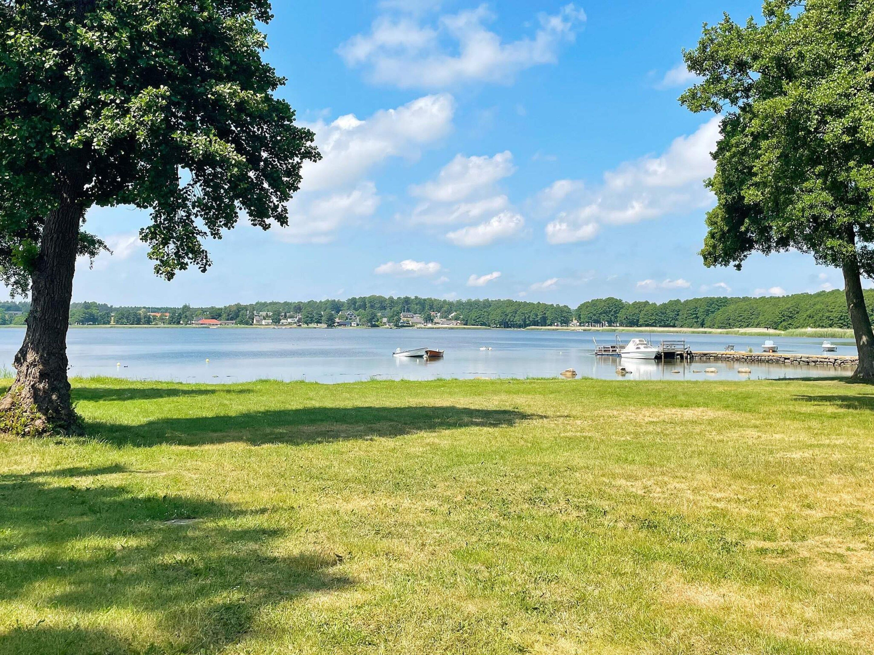 Une vue sur le lac, avec des bateaux amarrés, des pelouses et des arbres.