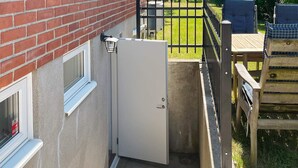 A residential property with a brick exterior, a white door, a small outdoor seating area with a table and chairs, and a metal gate. - 6 Person Holiday Home in Solvesborg (Sölvesborg)