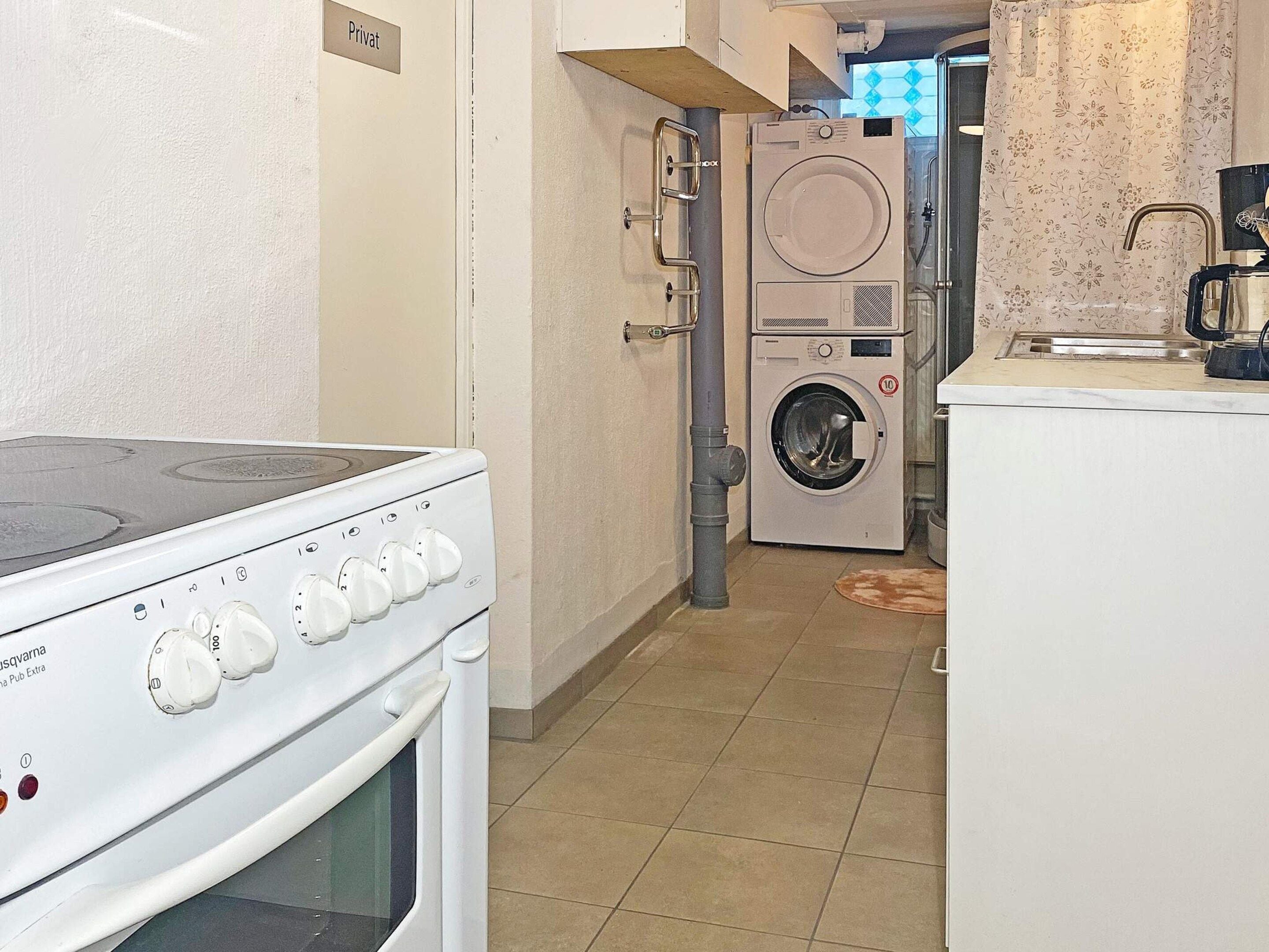 A kitchen with a stove, a washing machine, and a coffee machine.