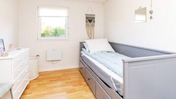 A bedroom with a bed, dresser, window, and wall-mounted mirror.