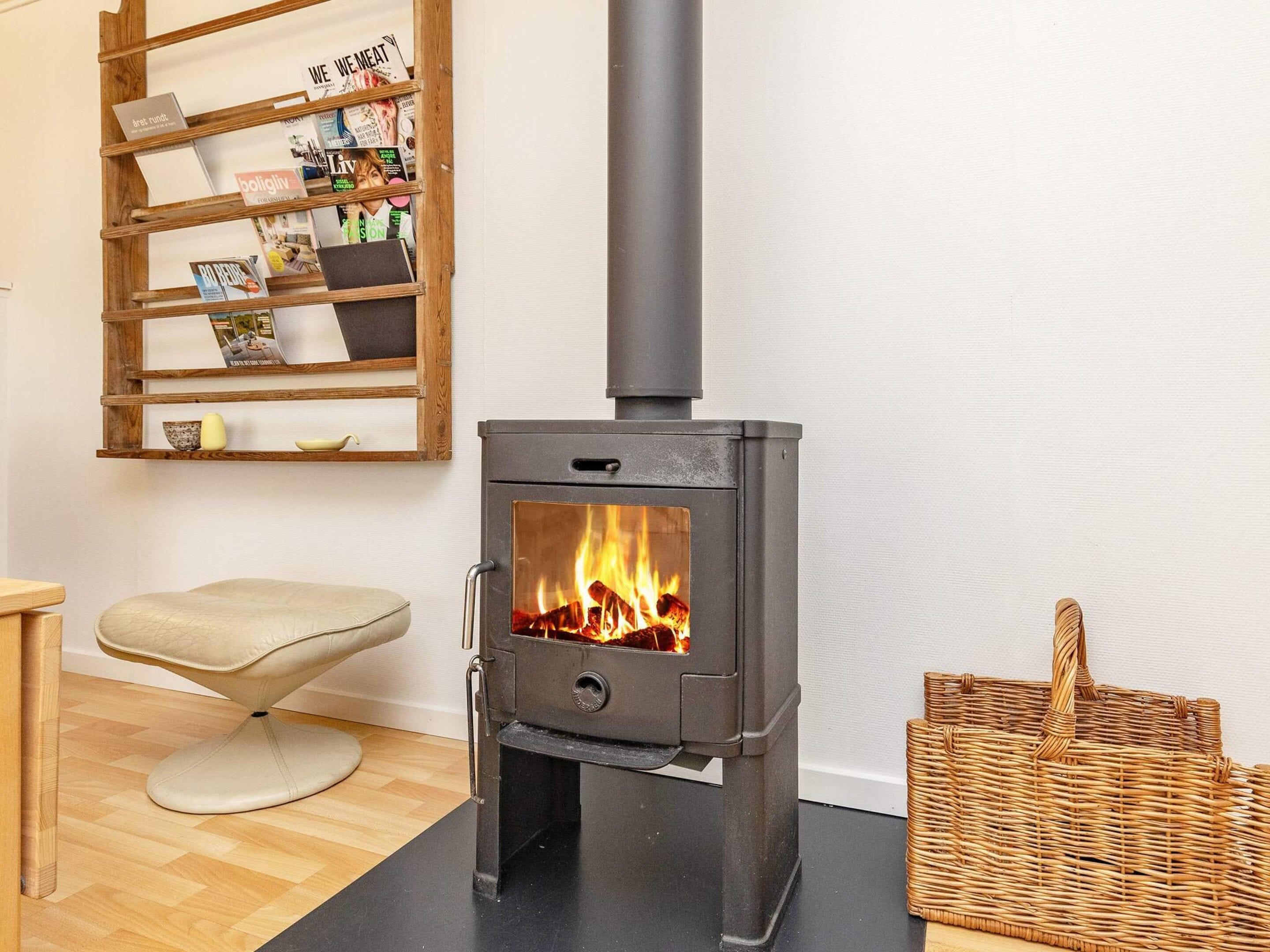 A room with a wood-burning stove, a wicker basket, and a chair.