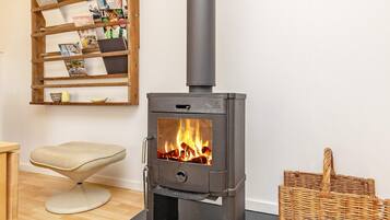 A room with a wood-burning stove, a wicker basket, and a chair.
