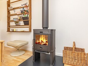 A room with a wood-burning stove, a wicker basket, and a chair. - 6 Person Holiday Home in Karrebaeksminde (Karrebæksminde)