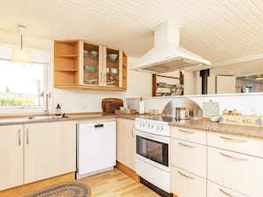 A modern kitchen with a dishwasher, oven, and wooden cabinets. - 6 Person Holiday Home in Karrebaeksminde (Karrebæksminde)