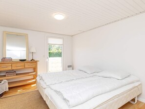 A bedroom with a bed, a dresser, a mirror, and a door leading to an outdoor area. - 6 Person Holiday Home in Karrebaeksminde (Karrebæksminde)