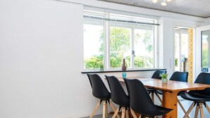 Ett modernt mötesrum med ett träbord, svarta stolar och stora fönster med utsikt över grönområden.