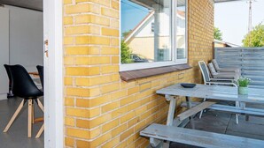 En uteplats med en mur av tegelstenar, ett fönster och utomhusmöbler.