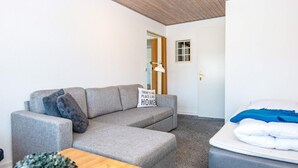 Ett modernt vardagsrum med en grå soffa, ett träbord och en säng med ett blått överkast.