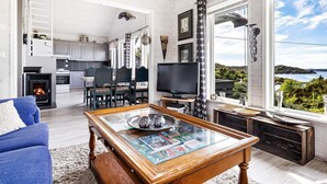 Una sala de estar con chimenea, televisor y un ventanal con vistas panorámicas.