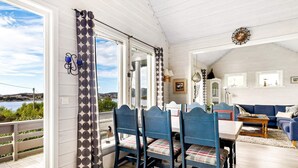 Una sala de estar acogedora con comedor, ventanas grandes y vistas al exterior.