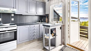 Una cocina moderna con armarios grises, encimera negra y vistas al mar a través de un ventanal grande.