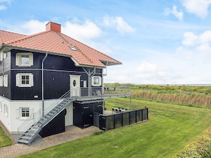 A two-story house with a red-tiled roof, a balcony, and a staircase leading to a garage. - 8 Person Holiday Home in Bogense (Bogense)