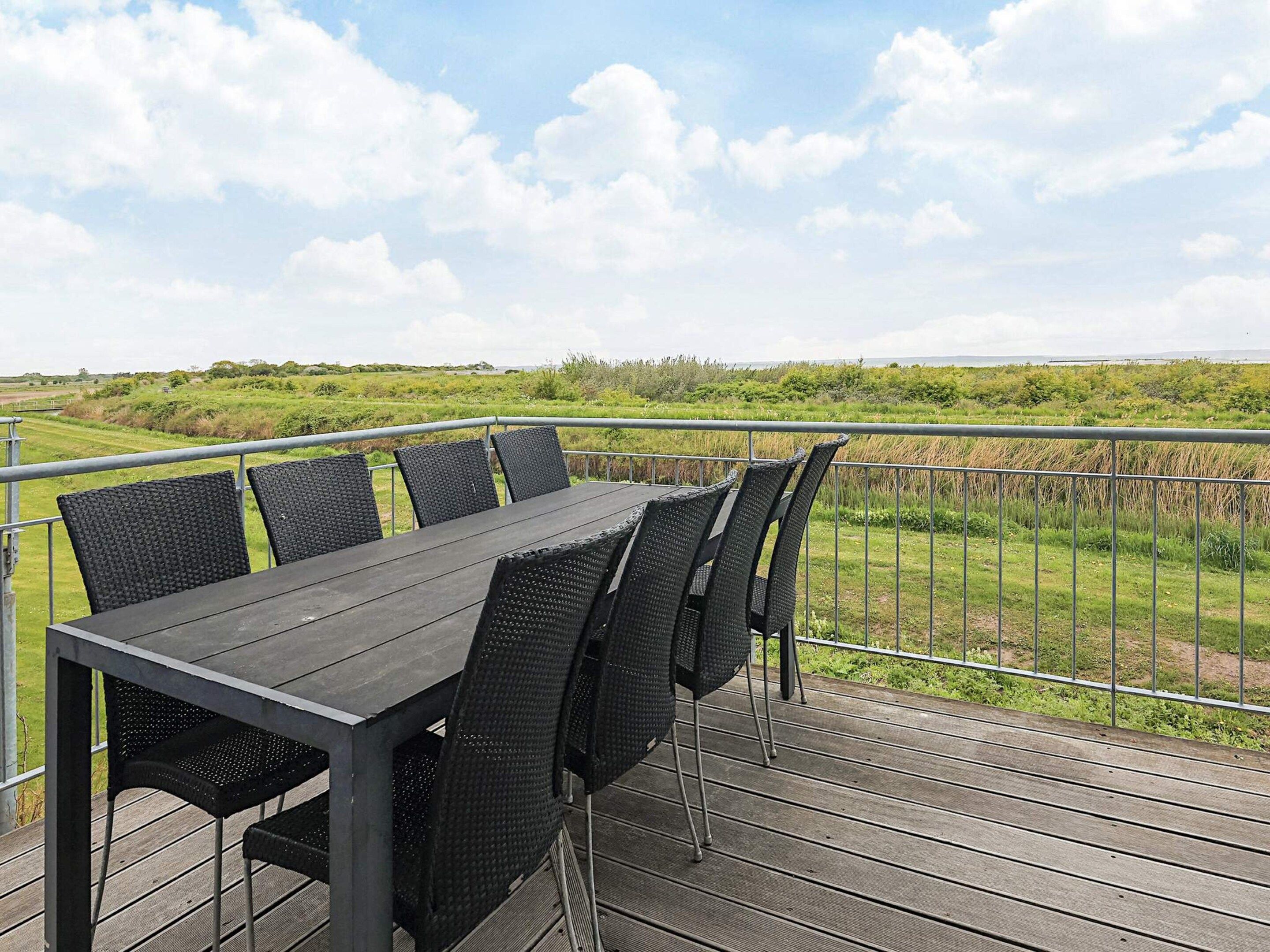 Eine Terrasse mit Tisch und Stühlen mit Blick auf eine Wiese.