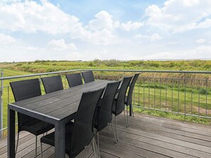 A deck with a table and chairs overlooking a grassy field.