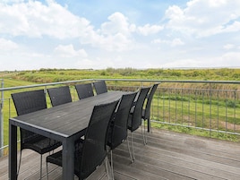 Una terraza con una mesa y sillas con vistas a un campo cubierto de césped.