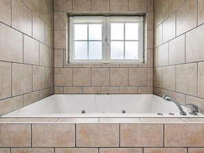 A bathroom with a bathtub, a window, and tiled walls. - 8 Person Holiday Home in Bogense (Bogense)