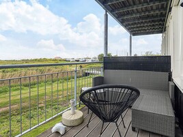 A balcony with wicker furniture, a stone planter, and a view of a marina.