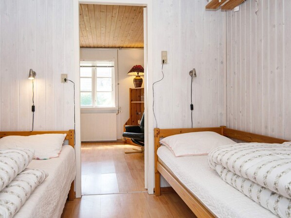 A room with two single beds, a wooden ceiling, a radiator, a window, and a chair. - 4 Person Holiday Home in Sydals (Sydals)