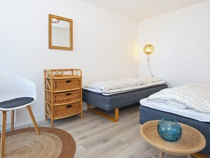 A bedroom with a bed, a chair, a dresser, and a lamp. - 8 Person Holiday Home in Ringkobing (Ringkobing)