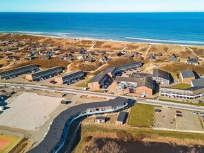 An aerial view of a coastal town with a marina, sandy beaches, and a variety of buildings including residential houses and commercial structures. - 8 Person Holiday Home in Ringkobing (Ringkobing)