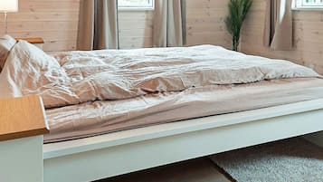A single bed with a wooden headboard, a bedside table, and a potted plant.