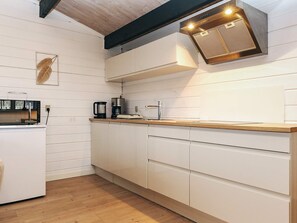 A modern kitchen with white cabinetry, a wooden countertop, a built-in oven, and a coffee maker. - 4 Person Holiday Home in Karrebaeksminde (Karrebæksminde)